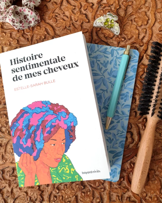 Si vous pensez que ce roman va vous parler de platitudes capillaires, vous n'y êtes pas du tout !
Ce livre utilise ce biais pour évoquer tout ce qui est important, dont en premier lieu, le racisme et la pression sociale dont Estelle-Sarah Bulle a été victime au travers des remarques incessantes sur ses cheveux crépus… Et c'est loin d'être une question anodine !
Tout commence par une résidence d'écriture un peu particulière, auprès de lycéens du CAP coiffure à Maryse Condé, a priori pas le public le plus facile pour ce style d'exercice littéraire (la plupart n'ayant pas forcément d'appétence pour les études classiques ou les cours de français… il va falloir leur montrer qu'ils ont tort, car ils ont aussi des choses à dire !).
Mais pour Estelle-Sarah Bulle, cette rencontre est aussi l'occasion de se plonger dans une histoire personnelle, qui est surtout l'histoire d'une émancipation qui l'a conduite à devenir une écrivaine qui s'engage et une femme qui s'assume.
De son enfance à Créteil dans les années 70, elle garde la trace des éternels questionnements sur la façon dont il a fallu dompter sa chevelure.
Un "problème" qui prend racine très tôt : née d'un père guadeloupéen et d'une mère du nord-est de la France, cette dernière n'avait pas forcément les "bons codes" pour coiffer sa fille "comme il aurait fallu" et on se chargeait bien de le lui faire remarquer à l'école ou en famille…
Des cheveux toujours "trop" : trop volumineux, trop crépus, trop difficiles… qu'il faut canaliser, éclaircir, lisser pour se conformer à l'image qu'attend la société française et entrer dans le moule de force (c'est particulièrement vrai dans le monde du travail ou dans certaines grandes écoles, comme si les cheveux afro étaient synonymes de négligence et devaient forcément être lissés pour que la personne puisse y être "assimilée").
Des remarques blessantes, racistes qui ont sans doute aussi forgé cette écriture de l'intime et une force qu'on sent jaillir de la plume et surtout de ses cheveux qui ne veulent plus être contrôlés !
⬇️suite⬇️